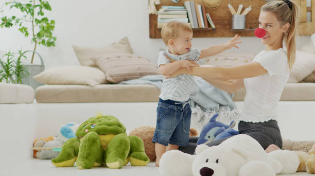 Happy and smiling mom with baby playing in living room at home with plush stuffed animals toys, sitting on the floor with pillows, caucasian blonde with blue eyes, healthy and love life growth concept Happy and smiling mom with baby playing in living room at home with plush stuffed animals toys, sitting on the floor with pillows, caucasian blonde with blue eyes, healthy and love life growth concept morning time management for preschool for babies stock pictures, royalty-free photos & images