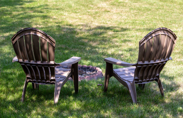istock Pair of lawn chairs in a back yard with light shade, around an extinguished fire pit 1335355800