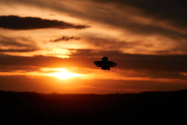 istock Small drone also multicopter as a silhouette. Orange evening sky with clouds, city in the background. Germany. 1335359779