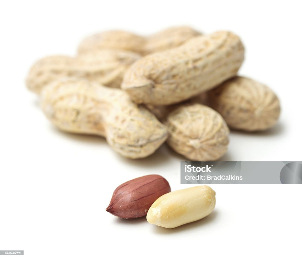 Peanuts focused in white background Peanuts in shells with two in front on white background Allergy Stock Photo