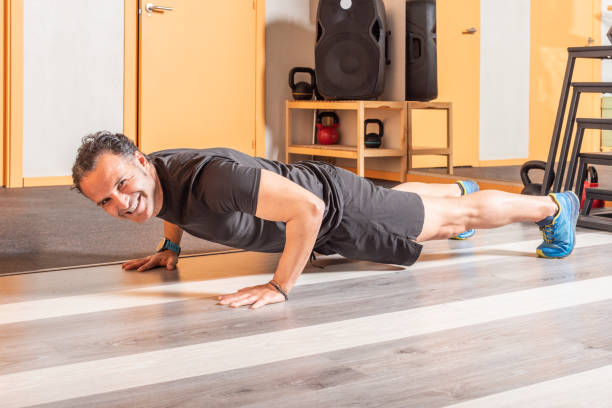 istock Adult man looking at camera doing push ups in helth club 1335362841