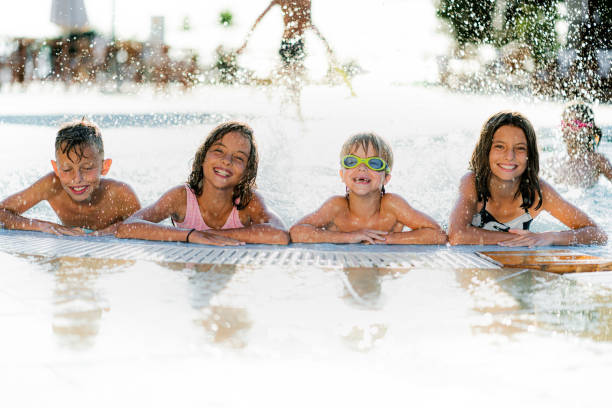 istock Playful kids having fun while splashing water in the swimming pool 1335366471