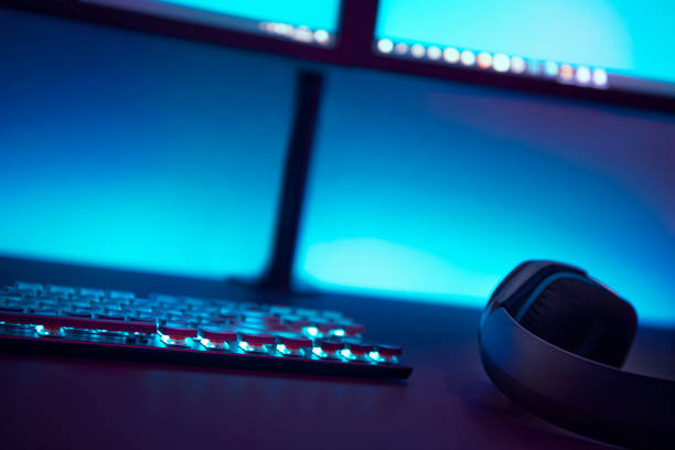 istock Low angle view of gaming accessories on dark table. Light blue illuminated wall in background. 1335368025