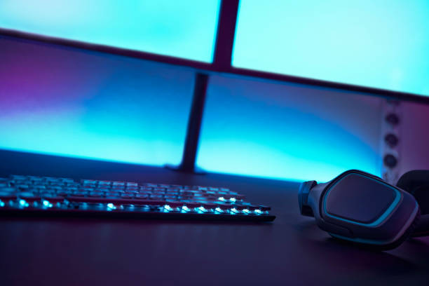 istock Low angle view of gaming accessories on dark table. Light blue illuminated wall in background. 1335368127