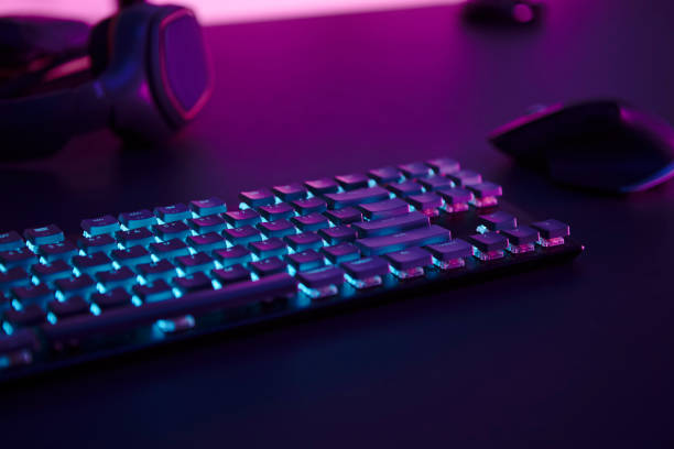 istock Computer gaming accessories, illuminated keyboard, mouse and headphones laying on desk. 1335368662