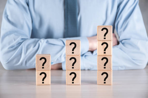 istock Businessman hold and put wooden cube block shape with question marks on grey table. Space for text.concept for confusion, question or solution 1335368877