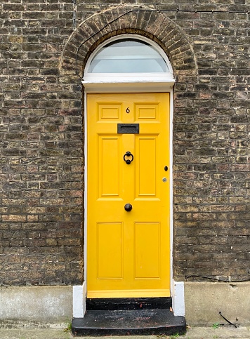 Fragment of facade of old georgian brick house with yellow arched door