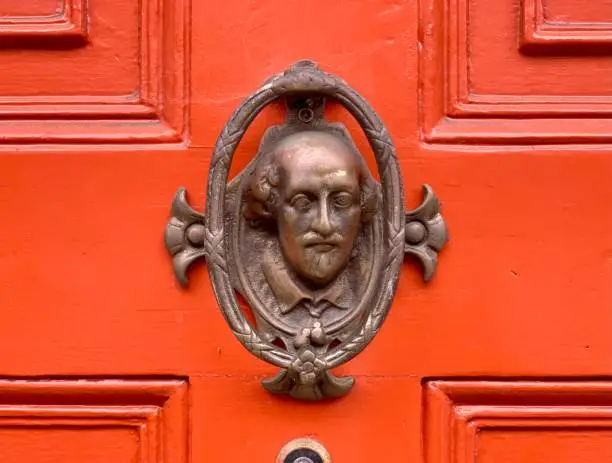 Orange door - freshly painted orange front door with bronze Shakespeare’s head as a door knocker