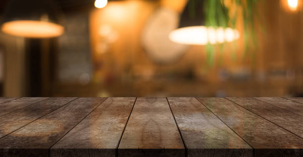 Empty wooden table top with lights bokeh on blur restaurant background.