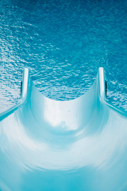 Blue swimming pool with water slide for background, high resolution. Summer vibes, active vacation concept.