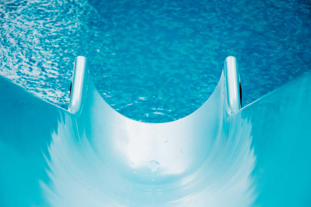 Blue swimming pool with water slide for background, high resolution. Summer vibes, active vacation concept.