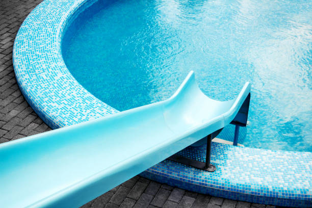 Round shaped swimming pool with blue water slide for background, high resolution. Summer vibes, hot weather, vacation concept.