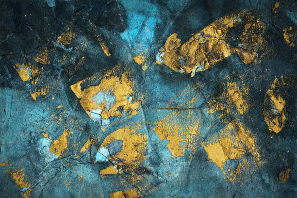 Abstract grunge hand painted gold paint stroke texture on a blue teal paper background