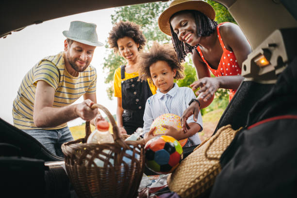 famiglia felice che scarica i bagagli dall'auto - car family picnic vacations foto e immagini stock