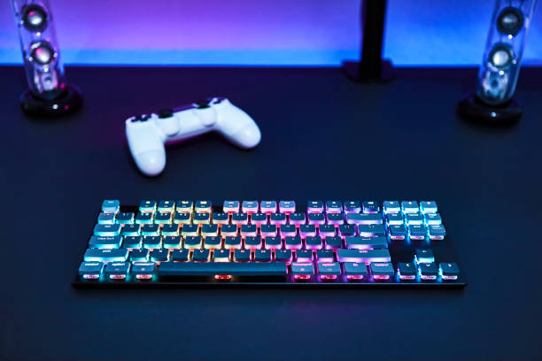 istock Various color backlighted gaming accessories laying on grey desk. Blue illuminated wall. 1335385659