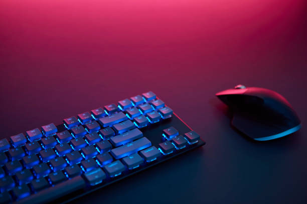 istock High angle view of backlighted keyboard and mouse laying on desk. Purple light from top. 1335385747