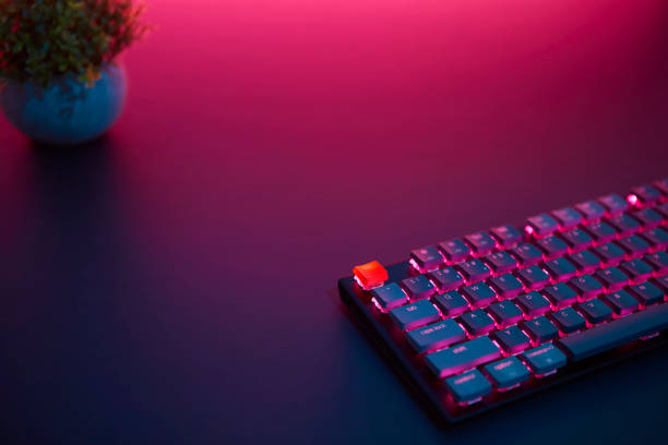 istock High angle view of gaming computer keyboard laying on desk. Purple light from top. 1335385769
