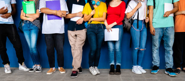 immagine banner orizzontale di un gruppo di studenti delle scuole superiori adolescenti multirazziali pronti a tornare a scuola in piedi contro il muro di sfondo blu. - school age girl foto e immagini stock