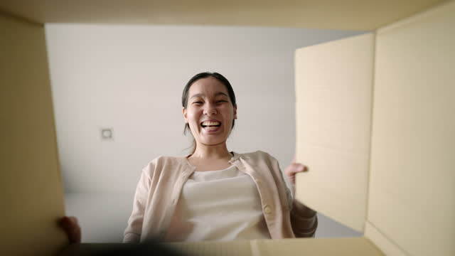 Asian Woman happily opens the parcel at home