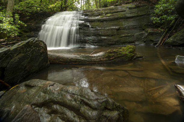 istock Boulders in foreground and water cascading down waterfall with layered rock formation 1335395817