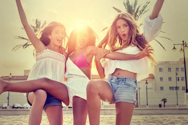 Best friends teen girls having fun on a beach sand at sunset