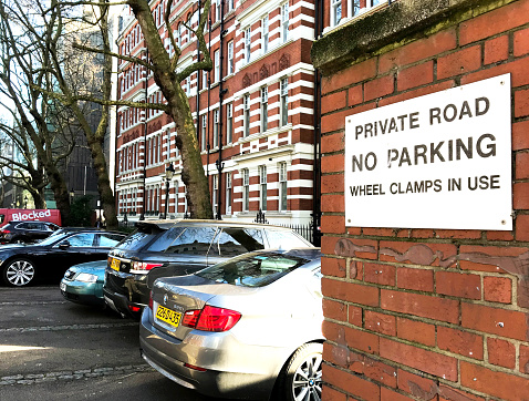 London, England - February 2018: No parking sign fixed to a wall on a private road in the city