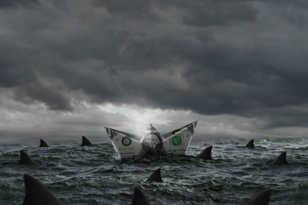 istock Boat made of a dollar bill surrounded by sharks 1335399701