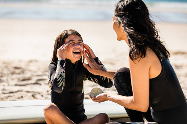 aussie mums helps her daughter apply natural sunscreen - women common 40s candid imagens e fotografias de stock