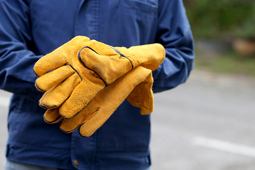 Hands of a man with gloves for pulling grass