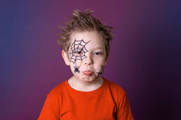 Cute little boy with Halloween makeup in gloomy emotions."nHalloween festive face painting concept. Cute little boy with Halloween makeup in gloomy emotions."nHalloween festive face painting concept. halloween face paint stock pictures, royalty-free photos & images