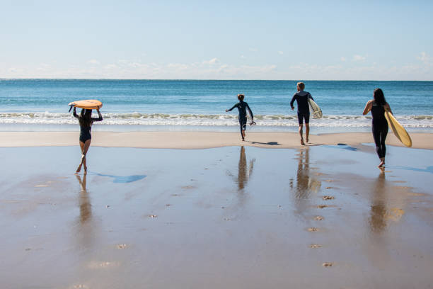 la famiglia australiana si dirige in acqua per un surf - surfing beach family father foto e immagini stock