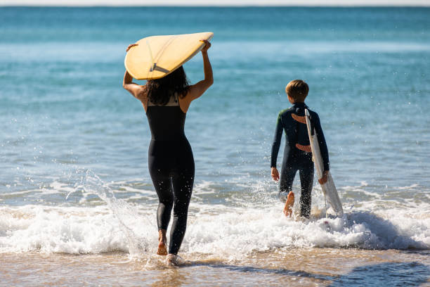 istock Surfing mum and son head into the water together 1335403666