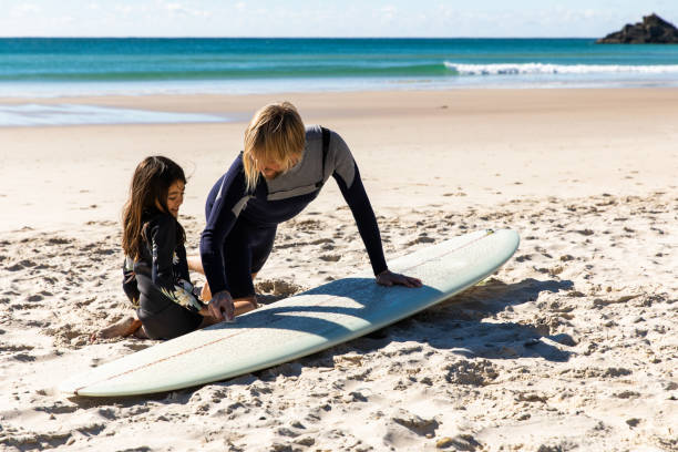 australijski tata uczy córkę, jak woskować deskę surfingową - surfing role model learning child zdjęcia i obrazy z banku zdjęć