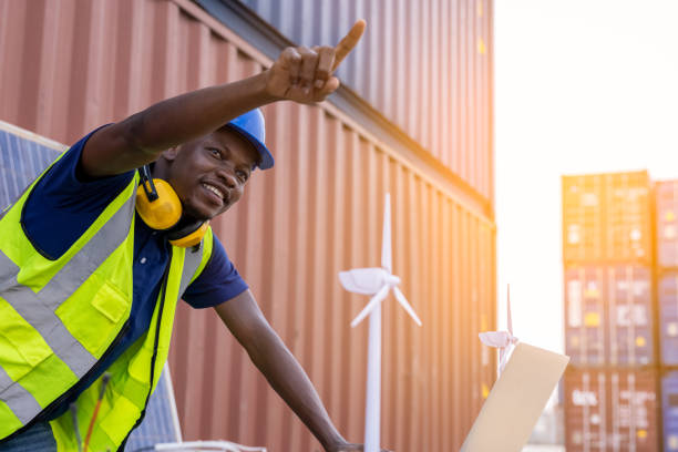 american black supervisor pointing fingers control workers and win turbine laptop with containers box background