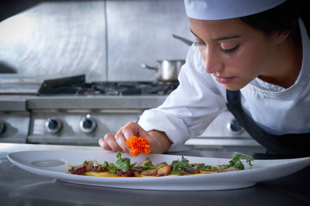 istock Chef woman garnishing flower in dish at kitchen 1335407563