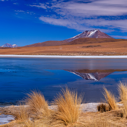 The Altiplano (Spanish for high plain), in west-central South America, where the Andes are at their widest, is the most extensive area of high plateau on earth outside of Tibet. Lake Titicaca is its best known geographical feature. The Altiplano is an area of inland drainage (endorheism) lying in the central Andes, occupying parts of Northern Chile and Argentina, Western Bolivia and Southern Peru. Its height averages about 3,750 meters (12,300 feet), slightly less than that of Tibet. Unlike the Tibetan Plateau, however, the Altiplano is dominated by massive active volcanoes of the Central Volcanic Zone to the west like Ampato (6288 m), Tutupaca (5816 m), Nevado Sajama (6542 m), Parinacota (6348 m), Guallatiri (6071 m), Cerro Paroma (5728 m), Cerro Uturuncu (6008 m) and Licancabur (5916 m), and the Cordillera Real in the north east with Illampu (6368 m), Huayna Potosi (6088 m), Ancohuma (6427 m) and Illimani (6438 m). The Atacama Desert, one of the driest areas on the whole planet, lies to the southwest of the Altiplano. In contrast, to the east lies the humid Amazon Rainforest.