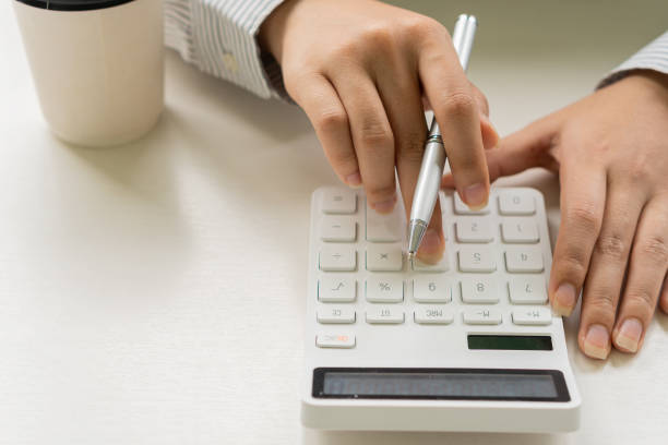 hand girl tenant un stylo et appuyant sur une calculatrice pour calculer les comptes financiers - check writing currency finance photos et images de collection