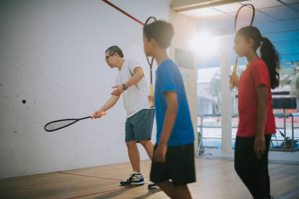 istock Asian squash coach guiding showing his student squash how to serve in the game 1335419062