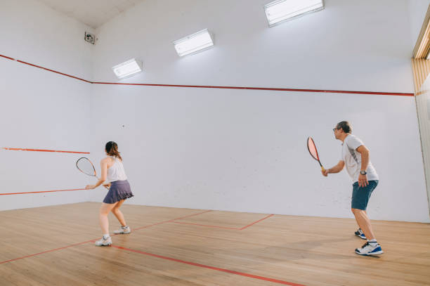 istock side view Asian squash coach father guiding teaching his daughter squash sport practicing together in squash court 1335419732