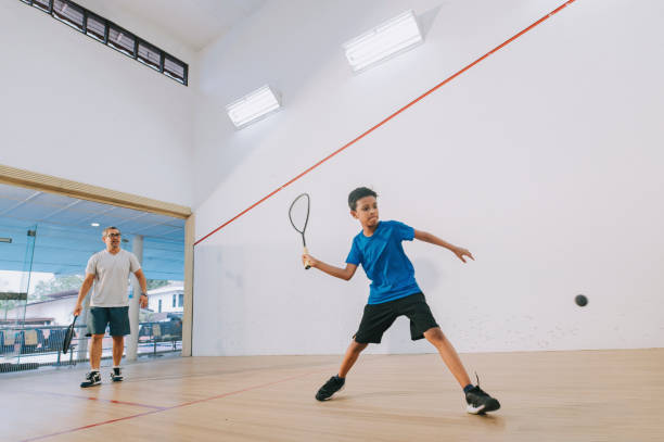 若いアジアのマレー男性スカッシュ選手は、彼のコーチからの指導と練習 - squash racket ストックフォトと画像