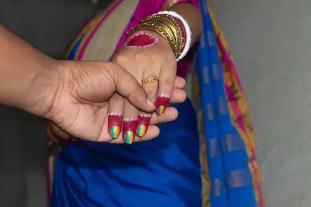An Indian groom holding the hand of the bride for the wedding promise. Selective focus on the wedding ring and fingers. Concept of love, faith, and beauty of marriage.