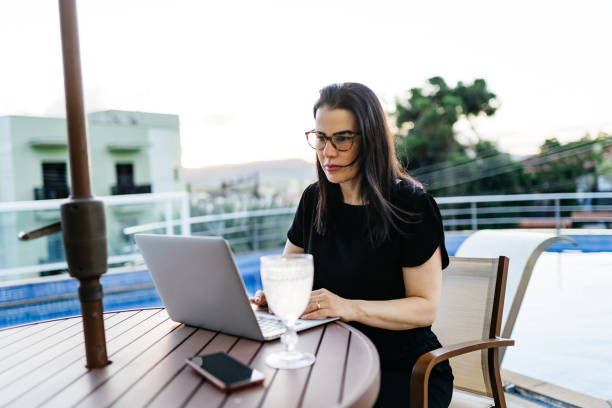istock Woman working on laptop beside the pool 1335421733
