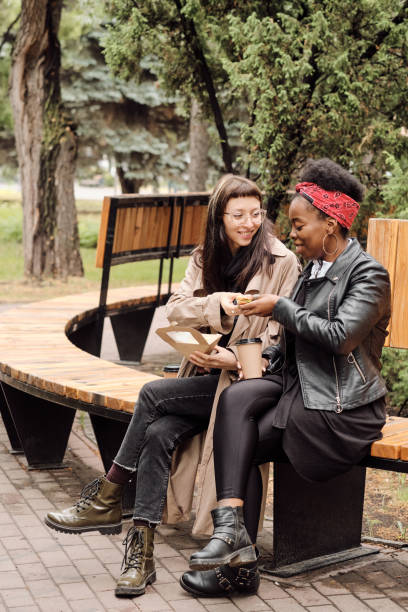 istock Two hungry girlfriends having snack and drinks in park 1335423072