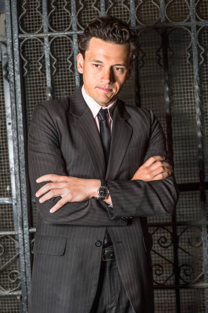 istock Young man standing by metal gate, thinking 1335430720