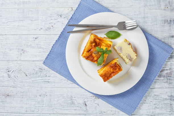 istock chicken breast and egg bake, chicken meat omelette on a white plate with silver fork and knife on a wooden table, horizontal view from above, flat lay, free space 1335431481