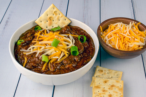 bowl of chili top with cheese and green onions
