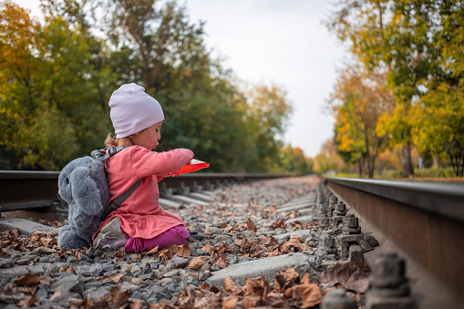 adorable toddler girl playing with a scoop on the railroad