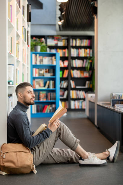 istock Young distracted man with open book looking aside 1335438589
