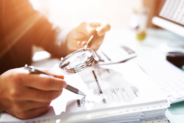 istock Audit And Fraud Investigation. Auditor Using Magnifying Glass 1335440169
