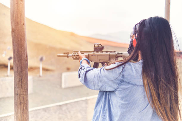 istock Woman empowered shooter aiming assault rifle at target. Selective Focus 1335443279